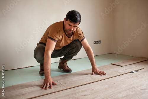 The man is putting laminate in the room at the home © Вероника Зеленина