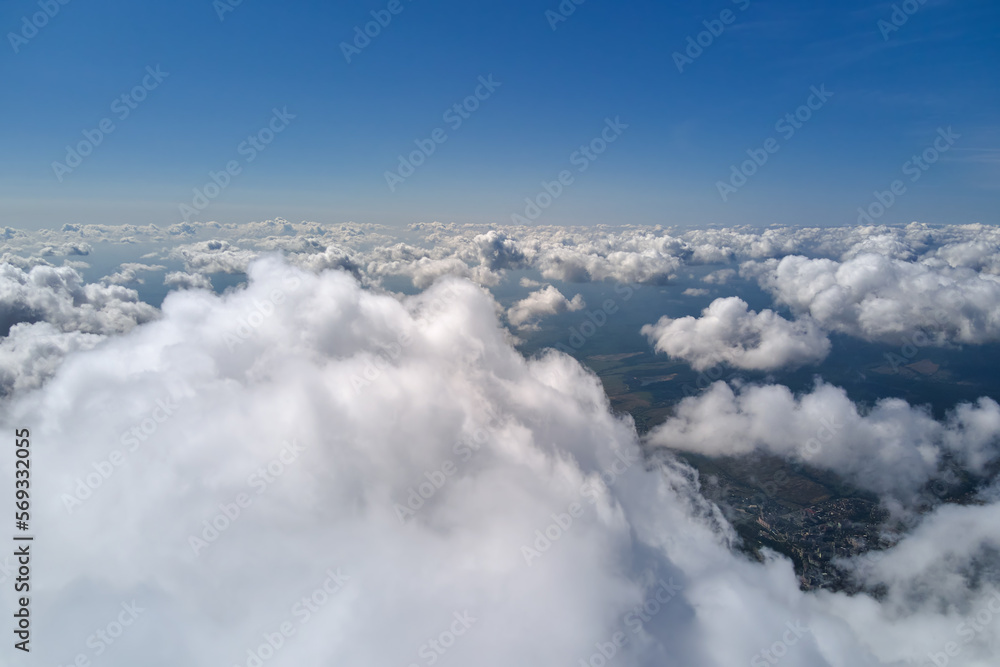 Aerial view from airplane window at high altitude of earth covered with white puffy cumulus clouds