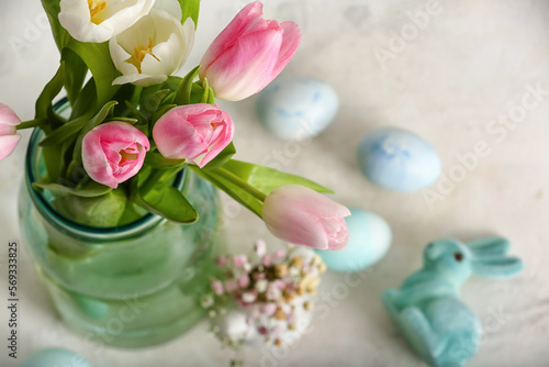 Vase with beautiful tulip flowers  Easter eggs and bunny on light background  closeup