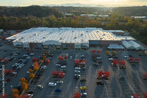 View from above of american grocery store with many parked cars on parking lot with lines and markings for parking places and directions. Place for vehicles in front of a strip mall center © bilanol