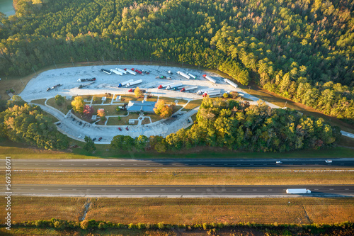 View from above of big parking rest area for cars and trucks near busy american highway with fast moving traffic. Recreational place during interstate travel