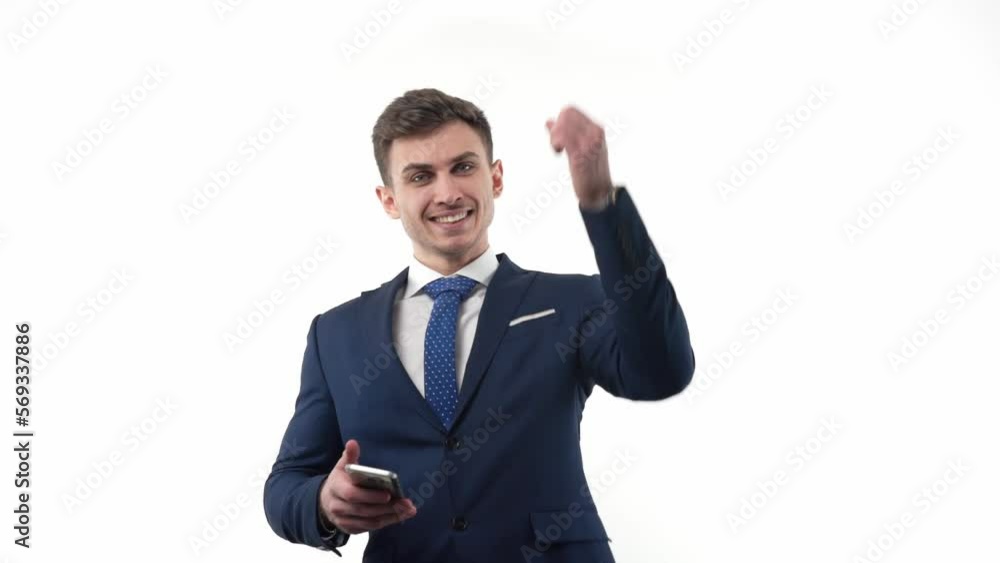 Young male businessman in a suit with a smartphone rejoices in winning lottery. Emotions are positive. Young male businessman in a suit with a smartphone rejoices in winning lottery. Emotions are positive.