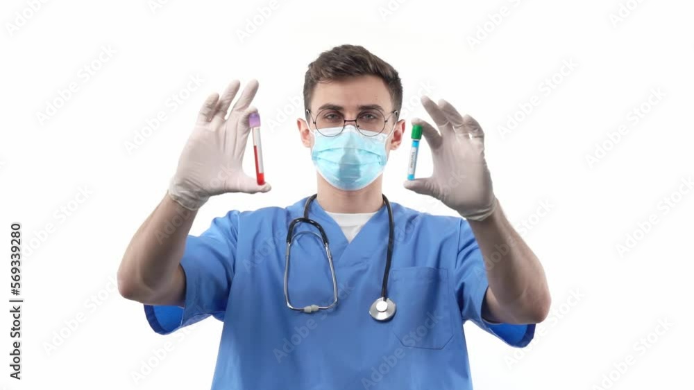 A young medic doctor chemist compares a test tube with a vaccine and a blood sample. The concept of mass vaccination. A young medic doctor chemist compares a test tube with a vaccine and a blood sample. The concept of mass vaccination.