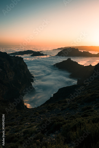 Pico do Arieiro is the third highest peak on Madeira Island and is one of the most popular sunrise spots.,a view from a drone of a landscape shrouded in clouds