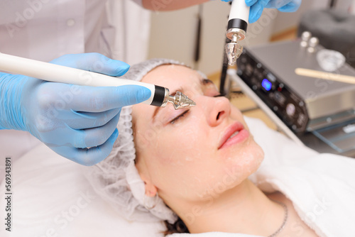 Wallpaper Mural cosmetologist conducts microcurrent facial therapy for a young woman using a device in a beauty salon. Hardware cosmetology, skin care, rejuvenation, regeneration. Torontodigital.ca