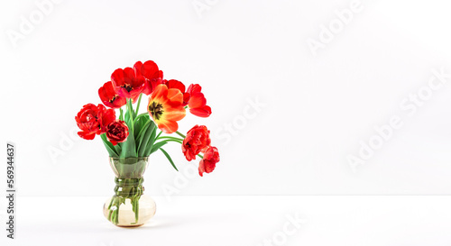 Big flowers bouquet of red tulips in vintage glass vase on white background. Copy space. Business card. Invitation postcard. Place for greeting text. International holiday. Banner. Hello spring