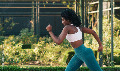 bella mujer negra saludable entrenando y corriendo en un parque al atardecer.
