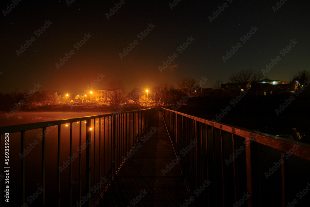 Bridge over a large river, starry sky, warm lights of the city
