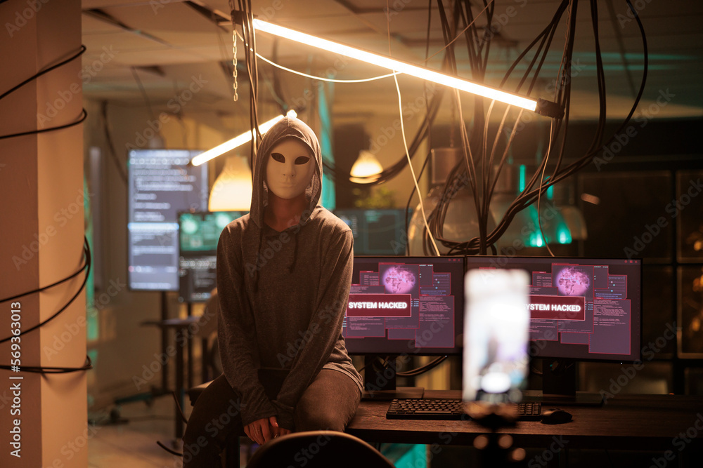 Anonymous hacker attacking database server portrait, cybercrime. Computer system hacking, information phishing, malware programming, cyber criminal in mask looking at camera at night time