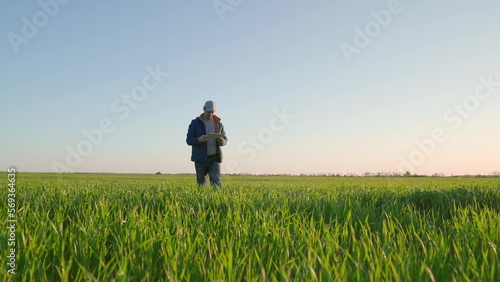 Working on farm with digital tablet in agriculture. Farmer with tablet evaluates with his hand shoots, green wheat sprouts in field. Technology of modern agriculture. Environmentally friendly © zoteva87
