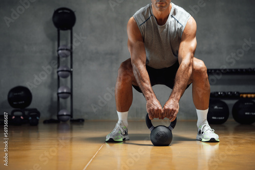 Athletic man lifting weight with kettle bell or dumbbell