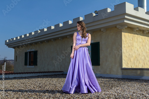 Young woman in a purple dress is standing on the roof of a building