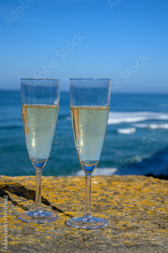 Glasses of champagne sparkling wine and view on blue Atlantic ocean, Lisbon area, Portugal