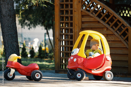 Portrait of cute little caucasain toddler boy enjoy having fun riding toy car in city park at spring day. photo