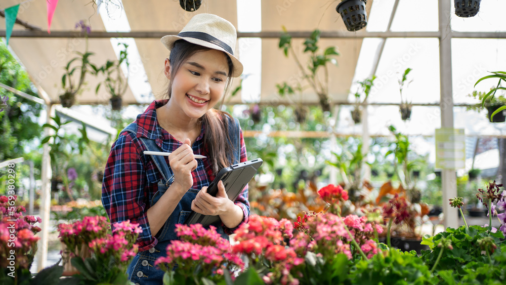 Modern technology in gardening business. Portrait of Asian female environmentalist using digital tablet in garden. Confident female is wearing apron while working. Modern technology in gardening business. Portrait of Asian female environmentalist using digital tablet in garden. Confident female is wearing apron while working.