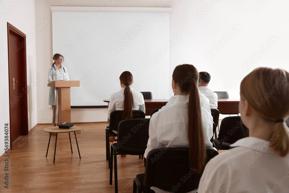 Doctor giving lecture in conference room with projection screen