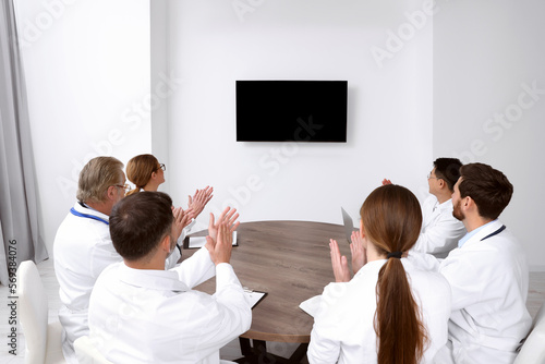 Team of doctors watching presentation on tv screen in room. Medical conference