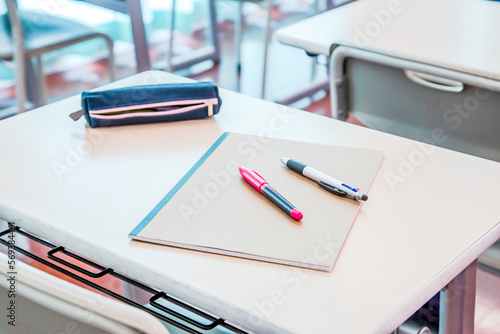 教室の机の上に置かれたノートとペン、ペンケース。学校生活のイメージ、背景素材