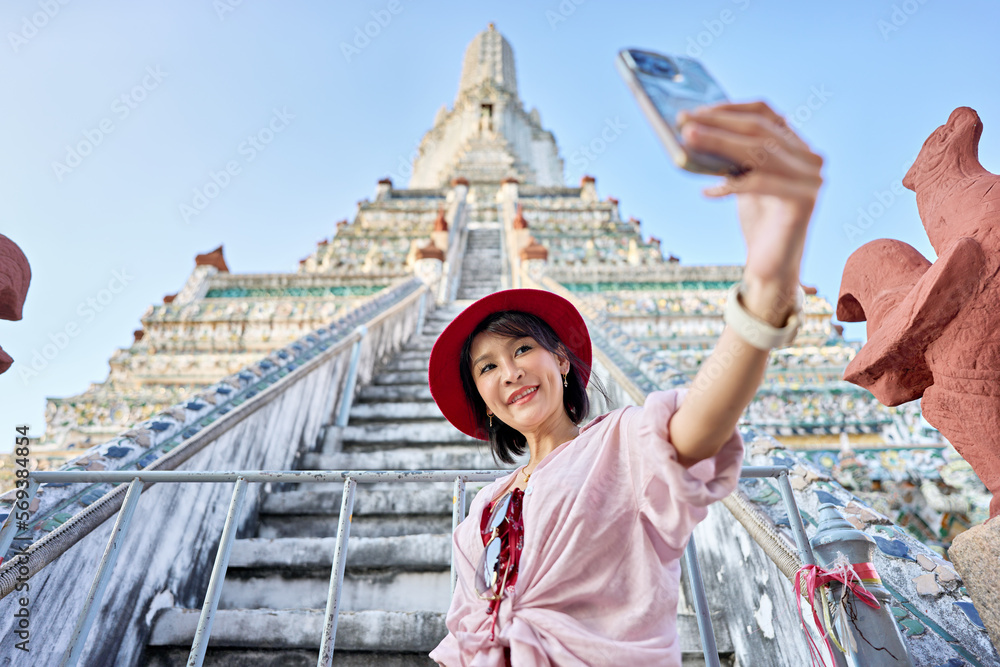 happy thai woman taking seflie at wat arun temple in bangkok thailand