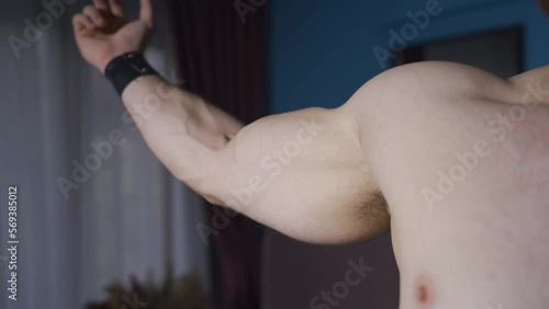 Muscular man practicing pose in a dark environment.
Bodybuilder man tightening his muscles in dark environment, experimenting with pose.
