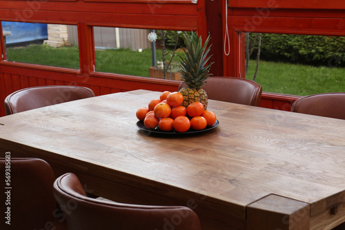 Fototapeta Naklejka Na Ścianę i Meble -  Wooden table with fruits and stylish chairs on terrace