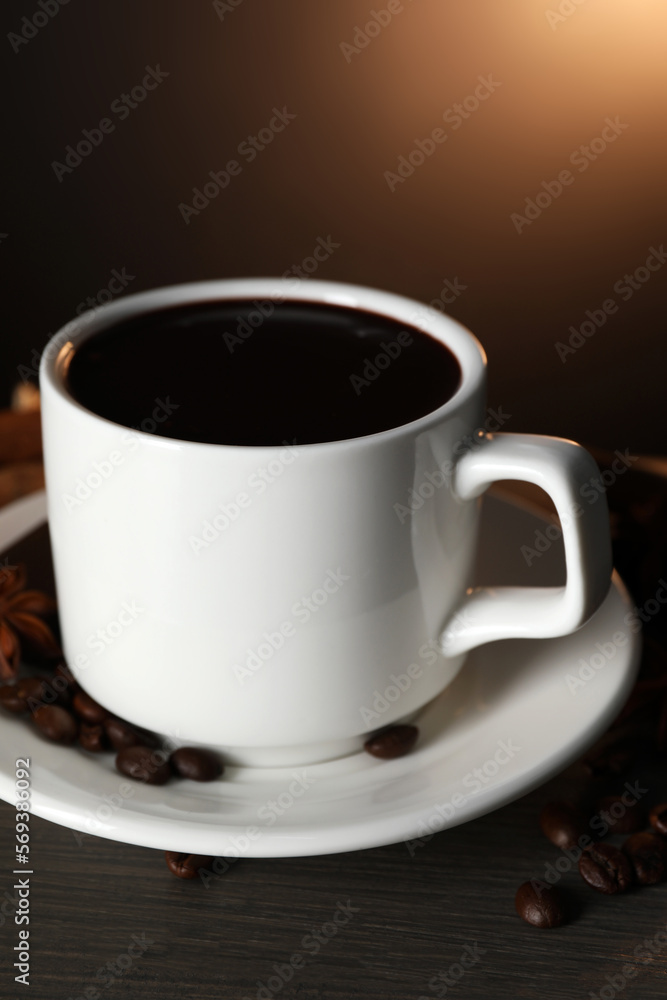 Cup of delicious hot chocolate and scattered coffee beans on wooden table Cup of delicious hot chocolate and scattered coffee beans on wooden table