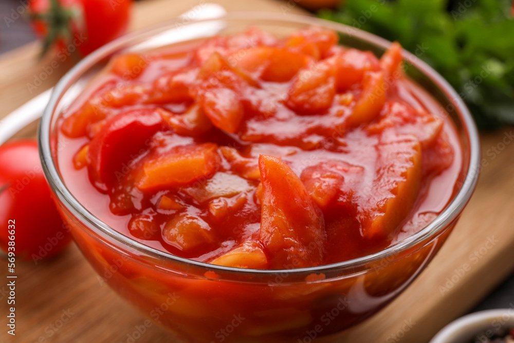 Delicious lecho in bowl on wooden board, closeup