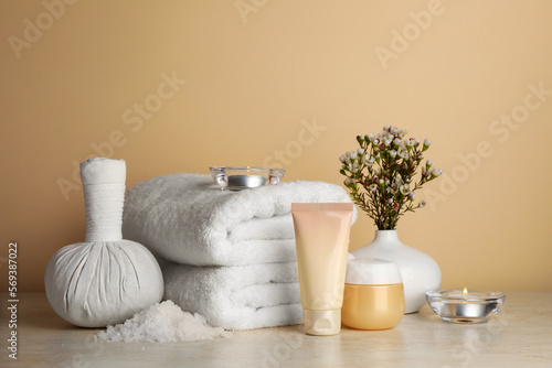 Composition with different spa products, candles and flowers on beige table
