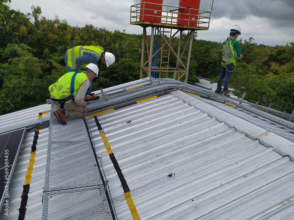 Engineers check and service installation solar cell on the roof of industry on the morning. Silhouette technician inspection and repair solar cell on the roof of industry. Engineers check and service installation solar cell on the roof of industry on the morning. Silhouette technician inspection and repair solar cell on the roof of industry.