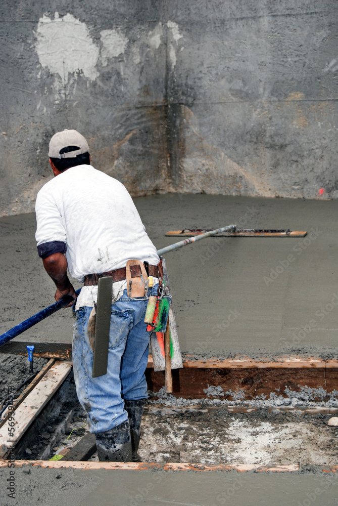 Mason using a bull float on freshly poured concrete Mason using a bull float on freshly poured concrete