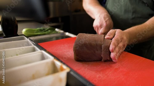 Chef cuts slice of tuna with knife photo