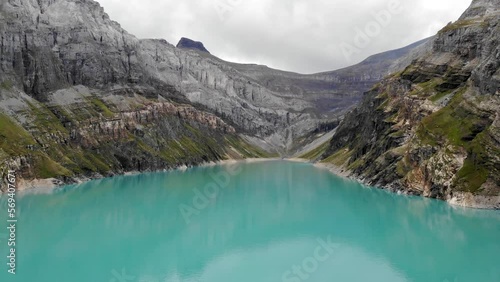 Aerial flyover over lake Limmernsee and hydroelectric dam in Linthal Glarus, Switzerland with a pan down view of the landscape full of cliffs to reflecting turquoise waters photo