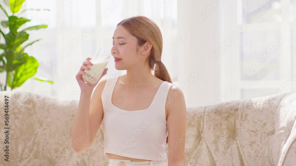 Healthy Young Asian woman Drinking milk with calcium for strong bone at home. Smiling indian woman holding soy milk on glass enjoy with nutrition wellness life.Wellness with natural milk fresh Concept Healthy Young Asian woman Drinking milk with calcium for strong bone at home. Smiling indian woman holding soy milk on glass enjoy with nutrition wellness life.Wellness with natural milk fresh Concept
