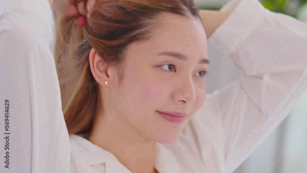 Beautiful Asian young woman tie the hair back before shower or apply cream or lotion on face. Beauty female grab her hairs after wake up with happiness and positive emotional. Self care concept