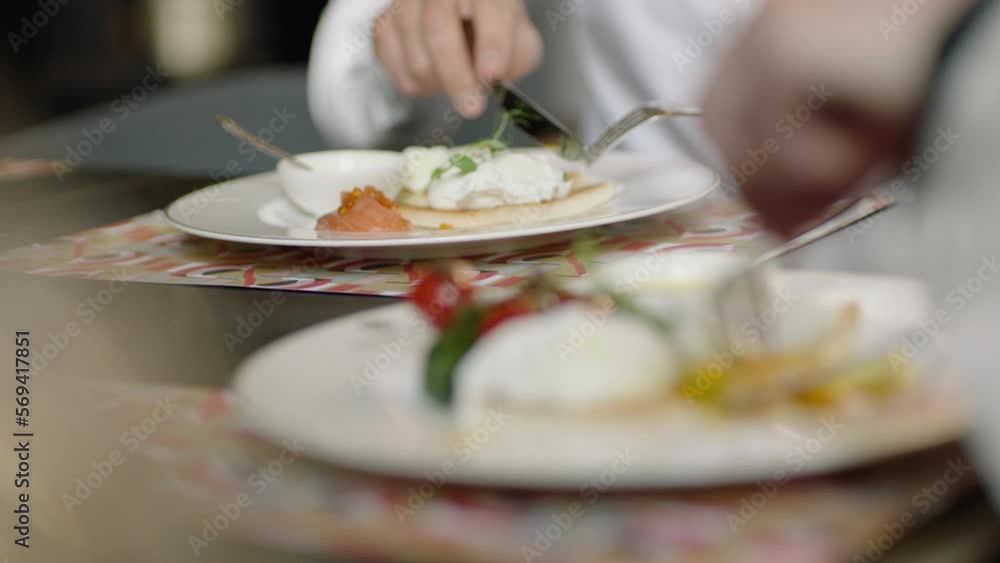 A couple of people have breakfast in a restaurant. Plates, utensils and hands close-up A couple of people have breakfast in a restaurant. Plates, utensils and hands close-up