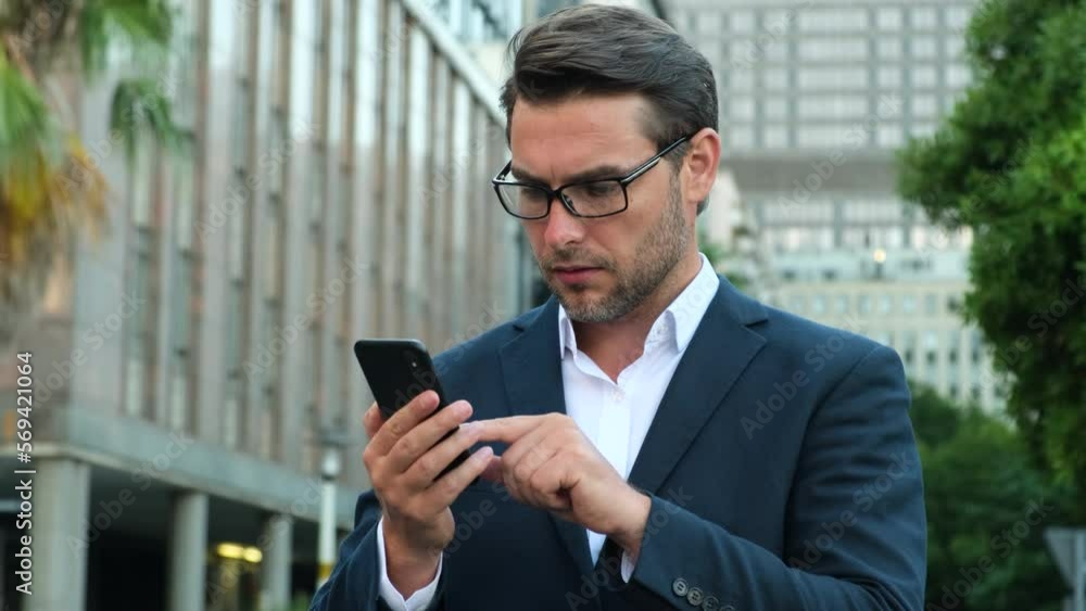 Male millennial professional holding modern smartphone texting message. Young businessman using helpful mobile apps for business time management organization concept. Male millennial professional holding modern smartphone texting message. Young businessman using helpful mobile apps for business time management organization concept.