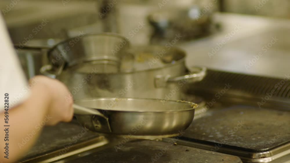 A professional chef skillfully prepares food on a frying pan. Frying pan and hands close-up A professional chef skillfully prepares food on a frying pan. Frying pan and hands close-up