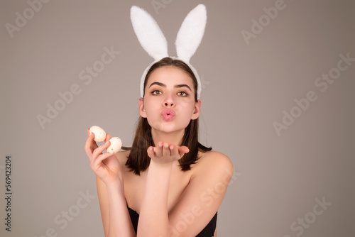Woman with bunny ears and easter eggs. Easter bunny isolated on studio background. Holidays, spring and party concept. Portrait of cute girl celebrating Easter.