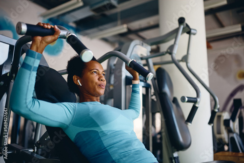 African American athletic woman using exercise machine during sports training in health club. photo