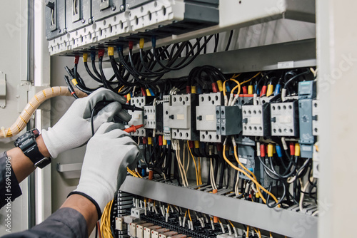 Electrician engineer tests electrical installations and wires on relay protection system.