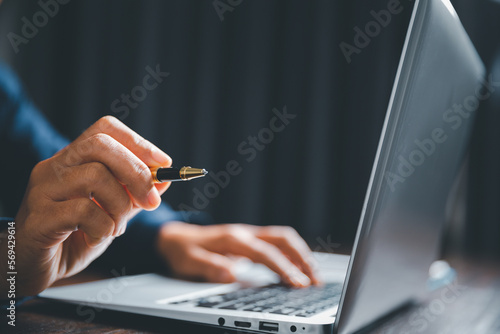 Closeup of businesswoman typing on laptop computer while sitting on table in office for design work, insert icons or business technology symbols. selective focus on hand. female online working on desk