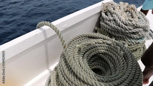 Slow Motion Shot Of Man Standing By Rolled Rope On Boat Over Sea During Sunny Day - Thulusdhoo, Maldives photo