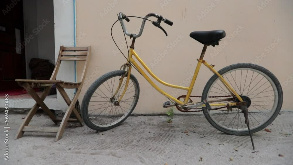 Slow Motion Shot Of Bicycle By Empty Wooden Chair Against House - Thulusdhoo, Maldives Slow Motion Shot Of Bicycle By Empty Wooden Chair Against House - Thulusdhoo, Maldives