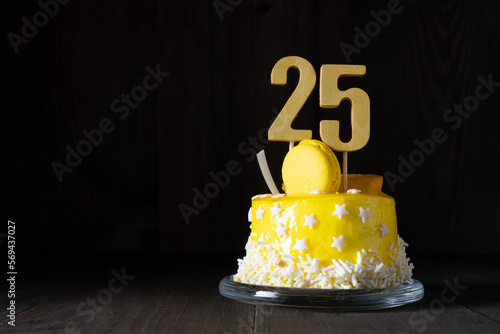 The number Twenty five on a yellow cake for an anniversary or birthday in a dark key. photo