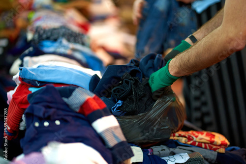 Person sorting second hand clothes by size and gender