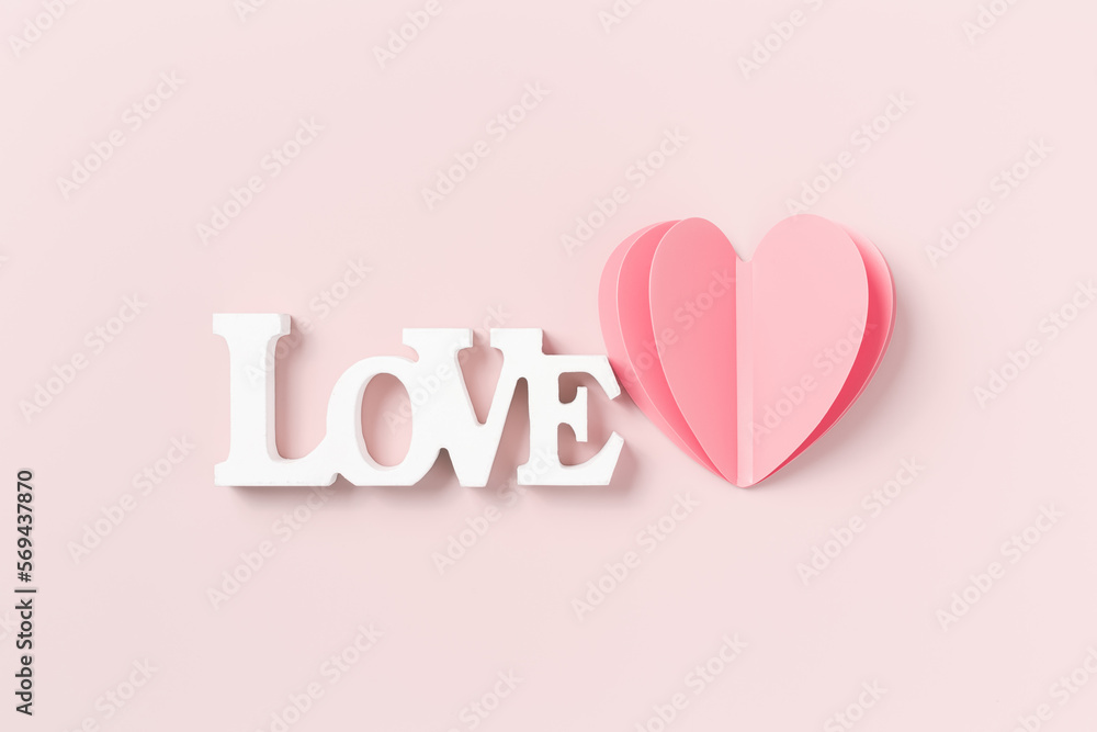 Pink heart and word love, happy Valentines Day, love or wedding day, holiday concept. Cut  paper heart and white wooden text love on pastel pink background, minimal aesthetic valentine card