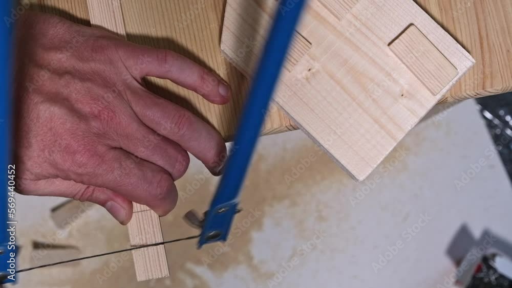 A man saws a small piece of board with a hacksaw A man saws a small piece of board with a hacksaw