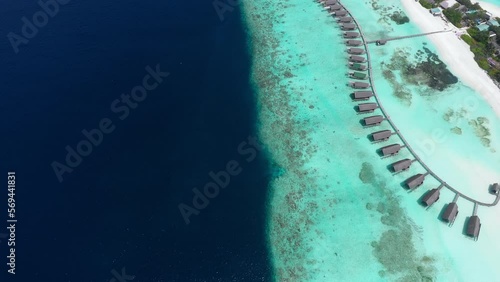 Aerial Shot Of Water Bungalows At Tourist Resort On Sunny Day, Drone Flying Over Turquoise And Blue Ocean - Thulusdhoo, Maldives photo