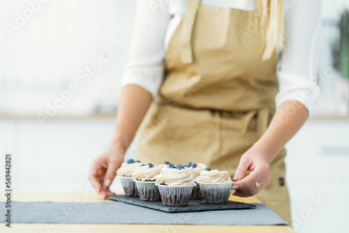 Women's hands of a confectioner, trim cupcakes with berries. Close-up, space for text