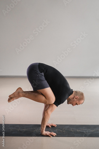 An athletically built man does yoga in the gym on a mat photo